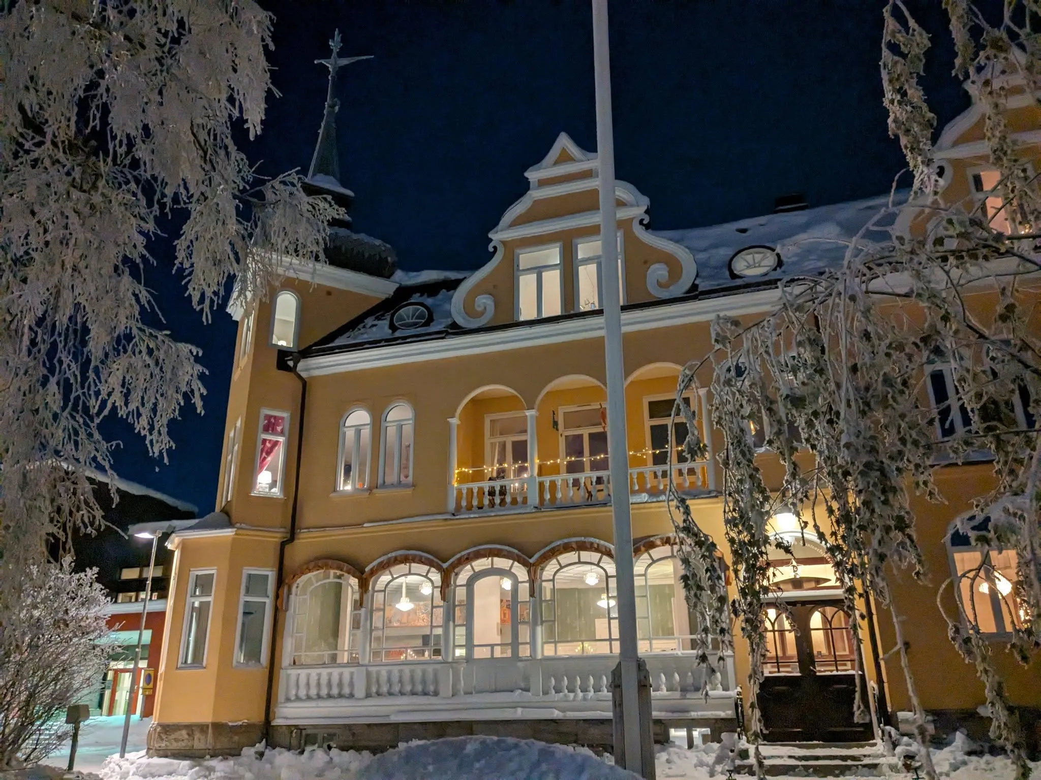 Temperance en vinternatt: det gula huset täckt av rimfrost, fönstren tända mot den mörka himlen.
